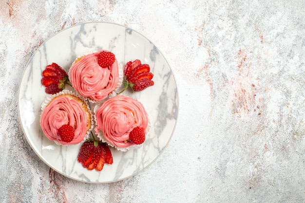 Foto grátis vista superior de bolos de morango rosa com morangos vermelhos frescos na superfície branca