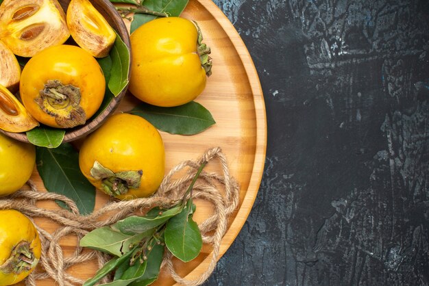 Vista superior de caquis doces e frescos em frutas maduras de mesa escura