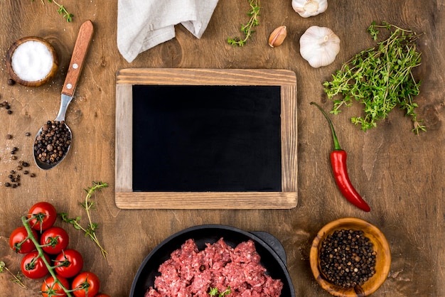 Foto grátis vista superior de carne com quadro-negro e tomate