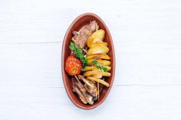 Vista superior de carne frita com verduras e ameixas assadas dentro de um prato marrom na luz, refeição com comida prato de carne jantar