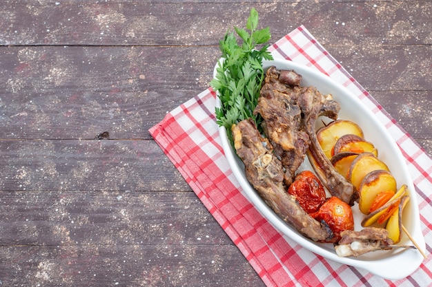 Vista superior de carne frita com verduras e ameixas assadas dentro do prato na mesa de madeira marrom, comida refeição prato carne jantar vegetais