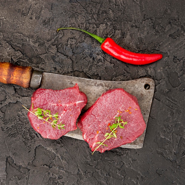Vista superior de carne no cutelo com ervas e pimenta