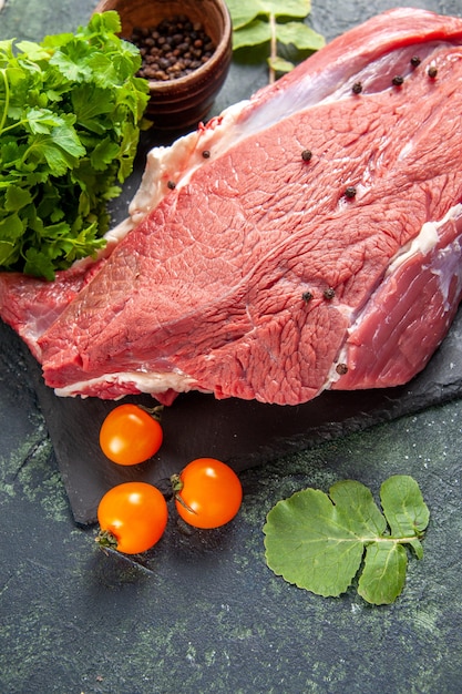 Vista superior de carne vermelha fresca crua em uma tábua de cortar tomate pimenta no fundo verde preto misturar cores