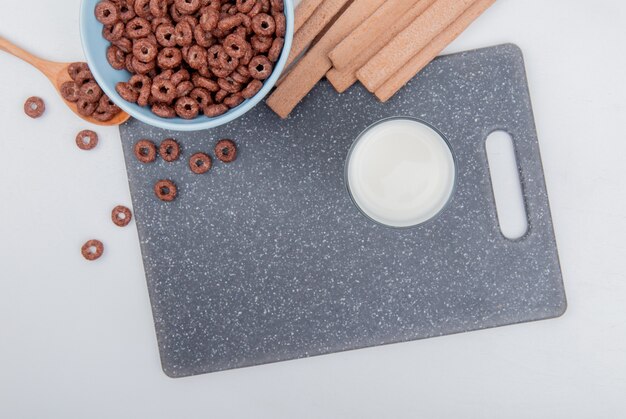 Foto grátis vista superior de cereais na tigela e na colher de pau com biscoitos na tábua no fundo branco