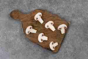 Foto grátis vista superior de cogumelos fatiados em uma tábua de madeira