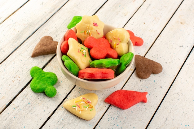 Vista superior de cookies deliciosos coloridos diferentes formados multicoloridos dentro da placa redonda