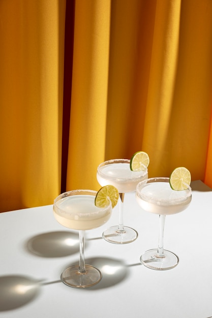 Vista superior de copos de coquetel margarita com borda salgada e limão na mesa branca