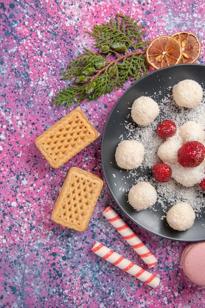 Foto grátis vista superior de deliciosas bolas de doces de coco com waffles e macarons na superfície rosa