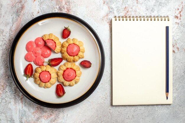 Vista superior de deliciosos biscoitos de açúcar com geleia de morango na superfície branca