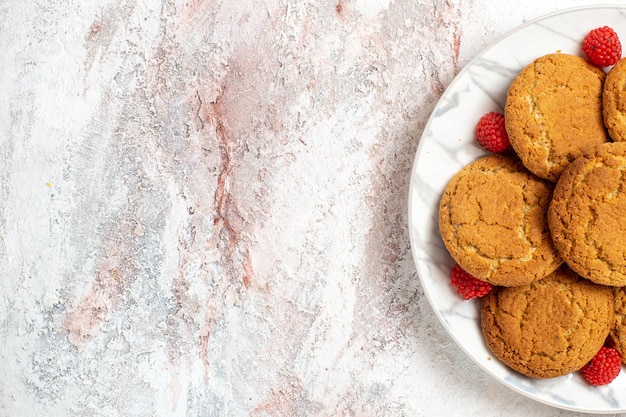 Vista superior de deliciosos biscoitos de açúcar dentro do prato na superfície branca