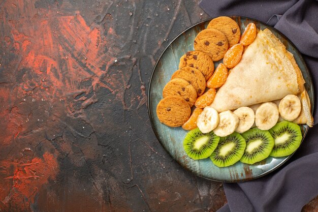 Vista superior de deliciosos biscoitos de crepe de frutas cítricas picados em uma toalha escura em cores diferentes