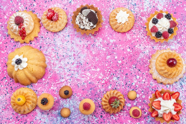 Foto grátis vista superior de deliciosos bolos assados com creme junto com diferentes frutas vermelhas, bolo biscoito baga doce assar chá