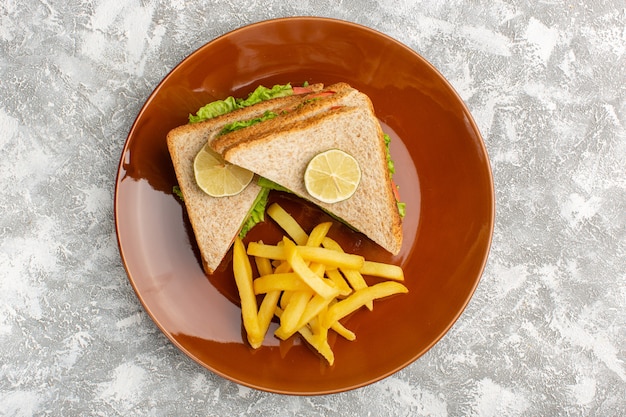 Vista superior de deliciosos sanduíches com salada verde de tomate dentro do prato marrom