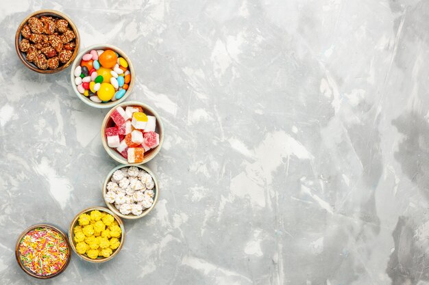 Vista superior de diferentes balas doces com marshmallows na superfície branca