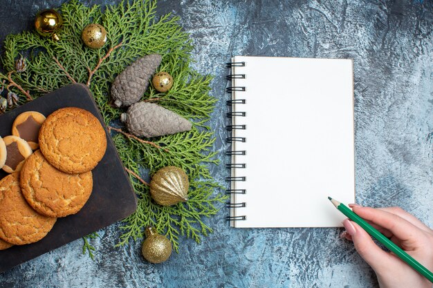 Vista superior de diferentes biscoitos saborosos com o bloco de notas na mesa de luz