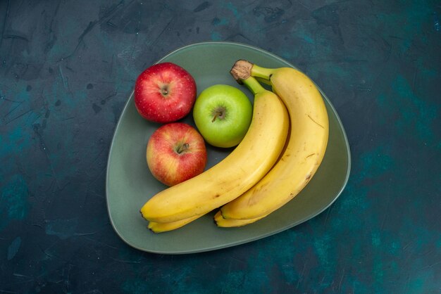 Vista superior de diferentes composições de frutas, maçãs e bananas, na mesa azul escura