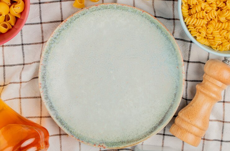 Foto grátis vista superior de diferentes tipos de macarrão em tigelas de manteiga de sal ao redor do prato na superfície de pano xadrez