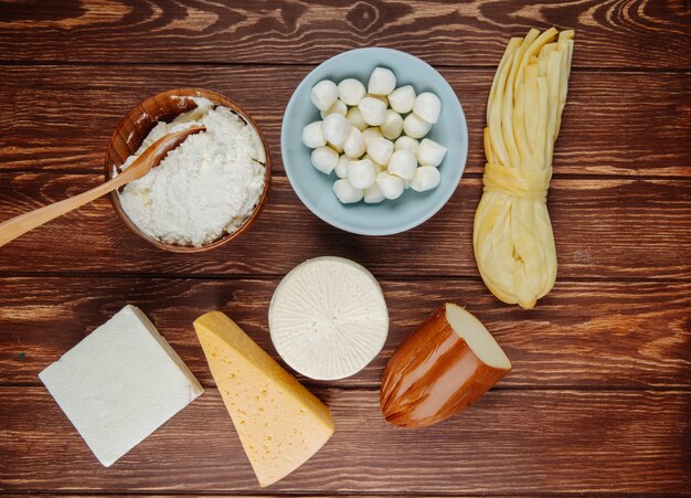 Vista superior de diferentes tipos de queijo na mesa de madeira rústica