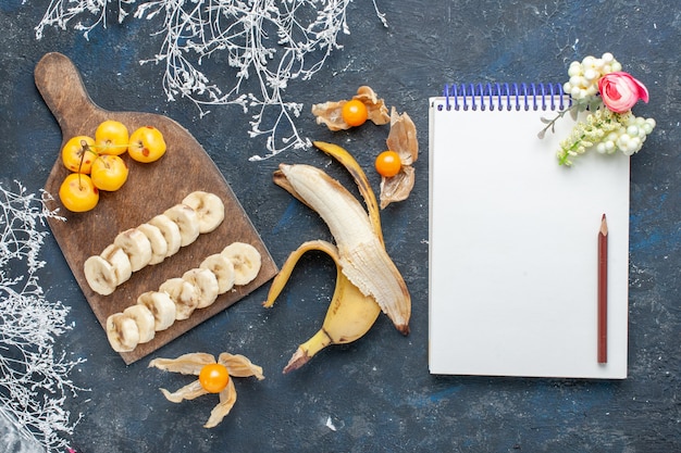 vista superior de doce e saboroso de banana amarela fresca fatiada com cerejas em bloco de notas em vitamina doce de frutas vermelhas escuras