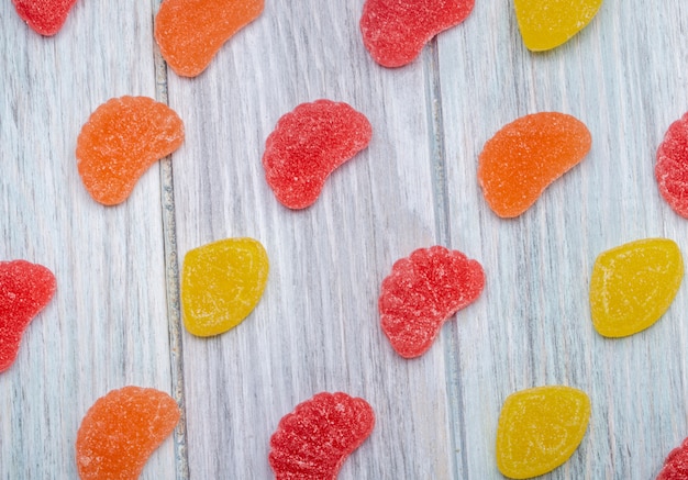 Foto grátis vista superior de doces de marmelada saborosos coloridos espalhados no rústico