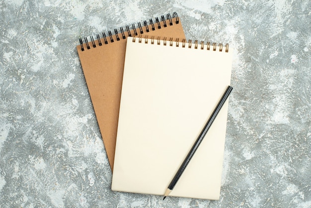 Vista superior de dois cadernos espirais kraft com caneta no fundo de gelo