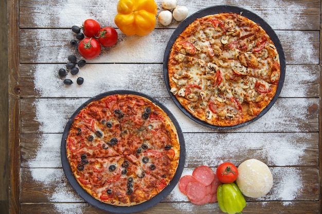 Vista superior de duas pizzas italianas em fundo de madeira com granulado de farinha