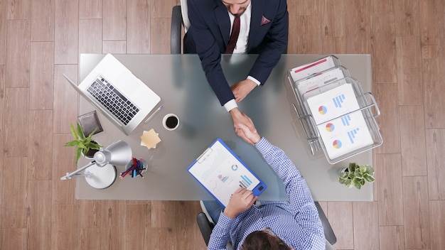 Vista superior de empresários apertando as mãos durante a negociação comercial no escritório de inicialização