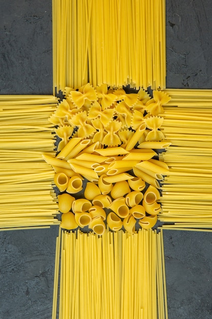 Foto grátis vista superior de espaguete cru com macarrão seco penne e farfalle no preto
