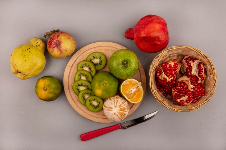 Foto grátis vista superior de fatias de kiwi fresco picado em uma cozinha de madeira com maçã verde e tangerina com marmelo-romã e maçã amarela isolada