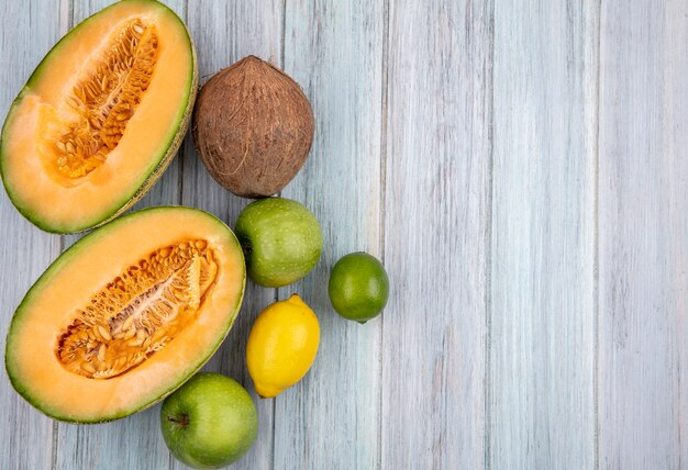 Vista superior de fatias de melão melão fresco com limão e coco em cinza com espaço de cópia