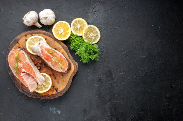 Vista superior de fatias de peixe fresco com rodelas de limão na mesa escura