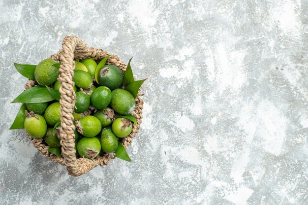 Vista superior de feijoas frescas em uma cesta de vime em uma superfície cinza isolada com espaço de cópia