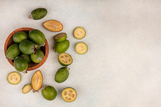 Vista superior de feijoas maduras frescas em uma tigela de madeira com feijoas isoladas em uma superfície cinza com espaço de cópia