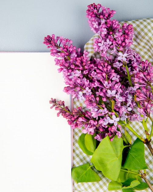 Vista superior de folhas de papel branco e flores lilás sobre fundo branco