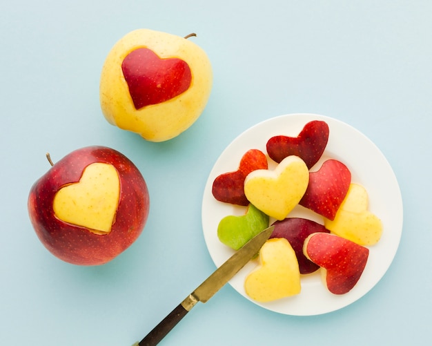 Vista superior de formas de coração de frutas no prato com faca