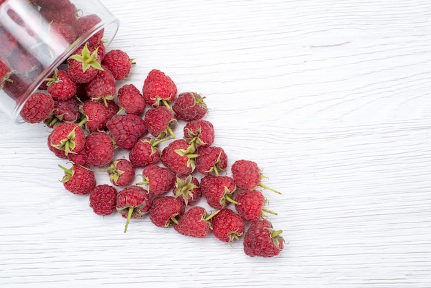 Vista superior de framboesas vermelhas frescas dentro e fora da tigela na luz, foto colorida de frutas frescas