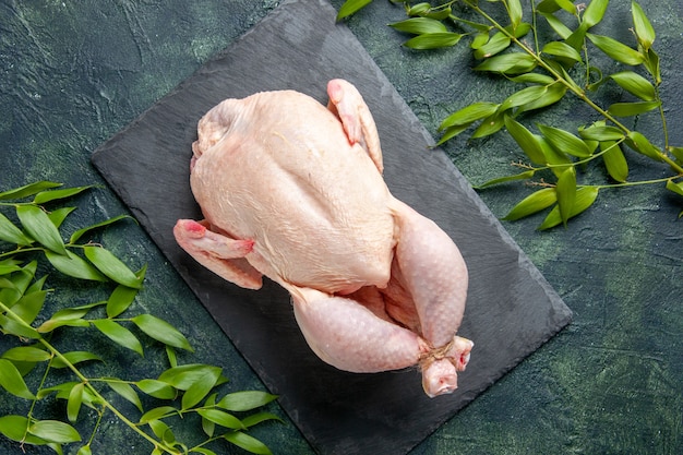 Vista superior de frango cru fresco com folhas verdes em fundo escuro farinha de frango foto de carne de animal comida cor cozinha