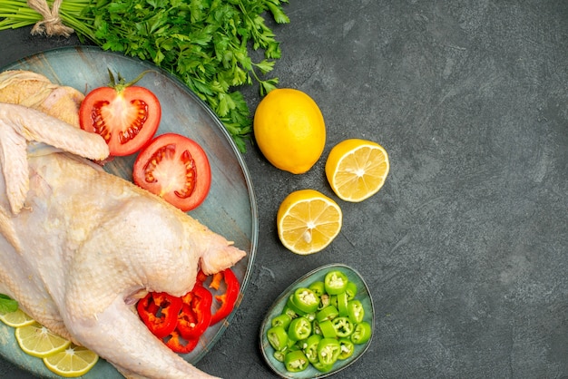 Foto grátis vista superior de frango fresco cru dentro do prato com verduras e legumes em fundo escuro