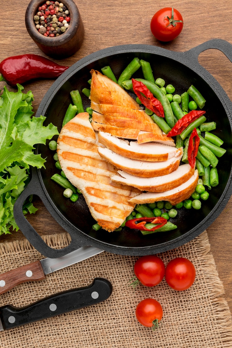 Foto grátis vista superior de frango grelhado e ervilhas na panela com pimenta e tomate