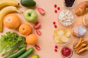 Foto grátis vista superior de frutas e legumes versus lanches não saudáveis