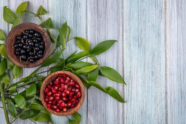 Vista superior de frutas em taças na superfície de madeira decorada com folhas com espaço de cópia