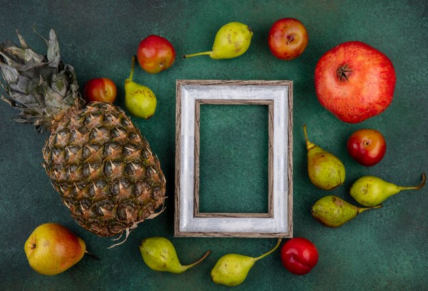 Vista superior de frutas em torno do quadro na superfície verde