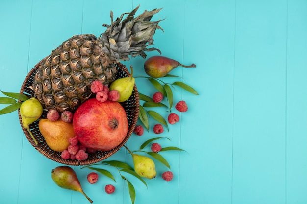 Foto grátis vista superior de frutas na cesta com folhas na superfície azul