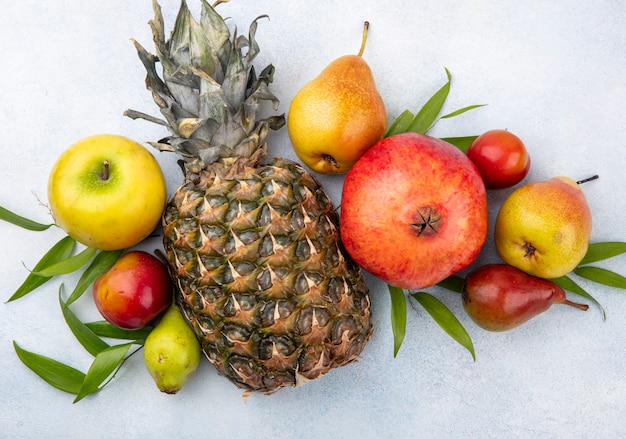 Vista superior de frutas na superfície branca, decorada com folhas