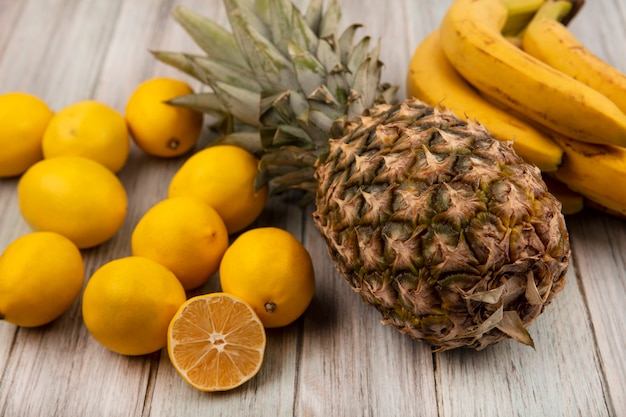 Foto grátis vista superior de frutas saborosas, como abacaxi, banana e limão, isolados em uma superfície cinza de madeira