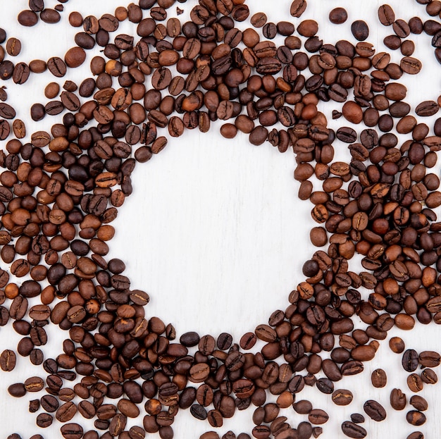 Vista superior de grãos de café torrados escuros isolados em forma de círculo em um fundo branco com espaço de cópia