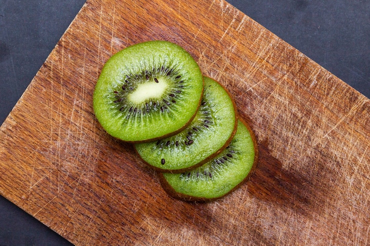 Foto grátis vista superior de kiwis fatiados em uma placa de madeira sobre a mesa