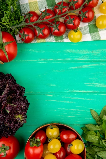 Vista superior de legumes como folhas de hortelã verde tomate manjericão na superfície verde com espaço de cópia