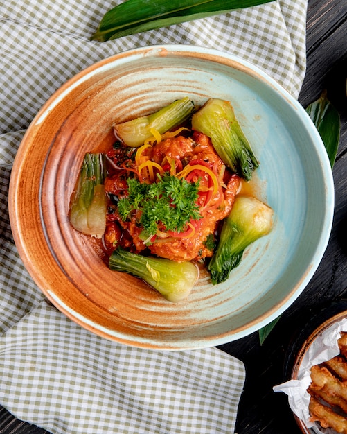 Vista superior de legumes cozidos em molho de tomate picante em um prato em tecido xadrez