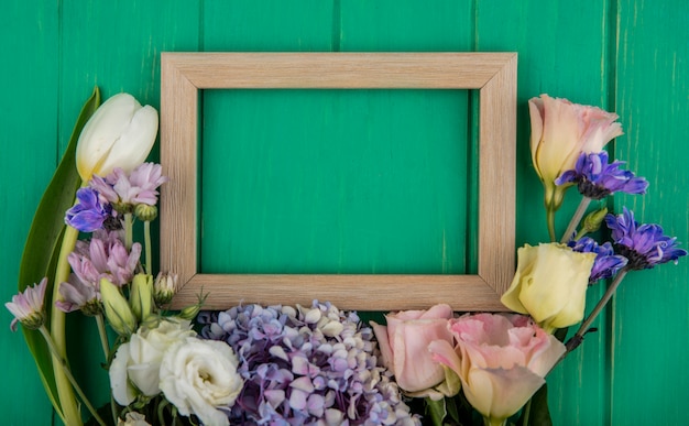 Vista superior de lindas flores coloridas, como a rosa da margarida de gardenzia em um fundo verde de madeira com espaço de cópia